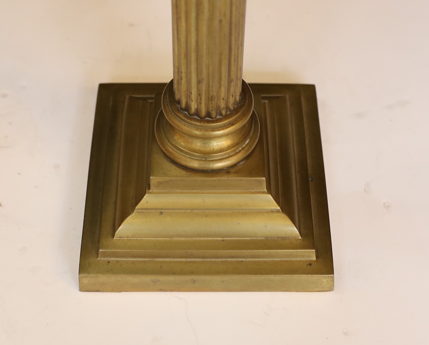 An Edwardian brass Corinthian column oil lamp with opaque pink glass reservoir, etched glass globe and flue, height overall 80cm
